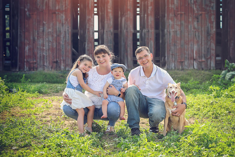 Dan and his A-1 family posing in the grass on a warm and sunny day with a fence in the background.